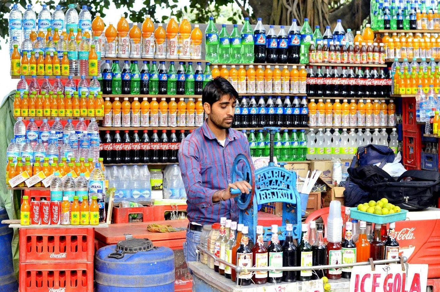 A shopkeeper standing in his drinks and grocery stall
